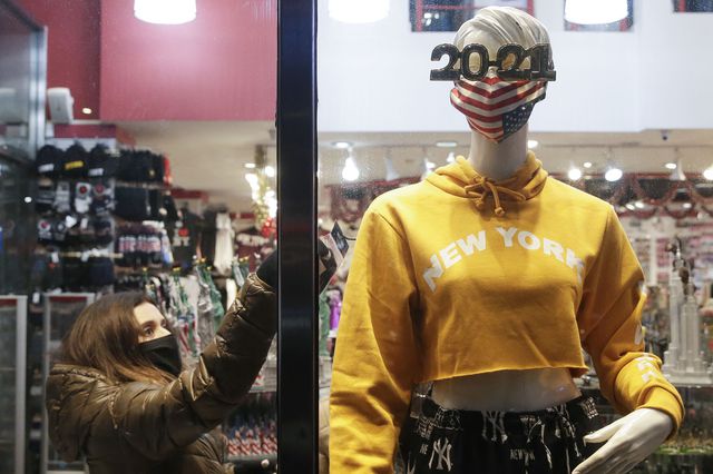 A girl checks the page on clothing from a mannequin that showcases an American Flag mask and 2021 NYE glasses a few blocks from Times Square which is closed to the public for the New Year's Eve celebration due to the coronavirus pandemic in Times Square.